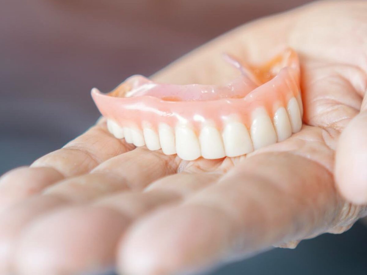 A full denture held in a hand